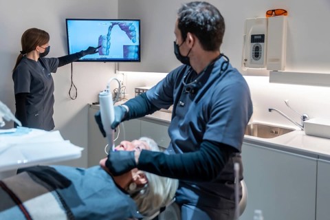 Dentist and assistant performing teeth whitening procedure using innovative 3d scanner technology,