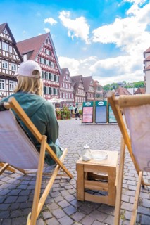 Person on a deckchair with a view of a street full of half-timbered houses, Calw, Black Forest,