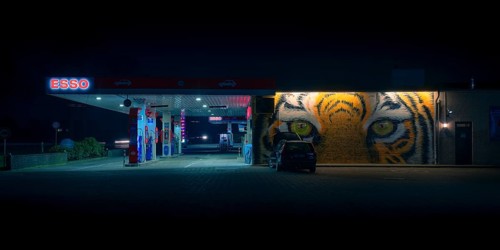 View of a petrol station with a parked car in front of a painted facade at night, Nienburg, Lower