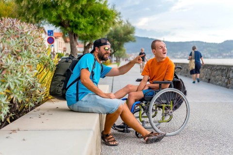 Disabled person in wheelchair with friends on summer vacation having fun