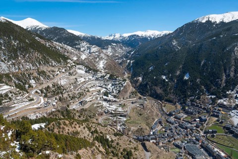 Verschneite Berge und ein Tal mit Straßen und verstreuten Gebäuden unter einem klaren blauen Himmel