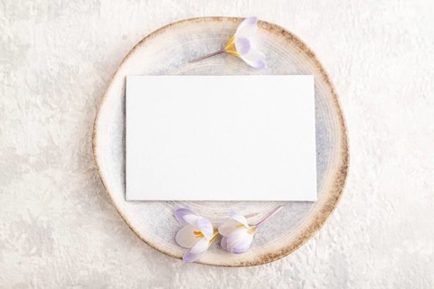 White paper invitation card, mockup with crocus flowers on ceramic plate and gray concrete