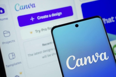 Canva logo is displayed on a smartphone screen, with the canva website visible on a computer screen