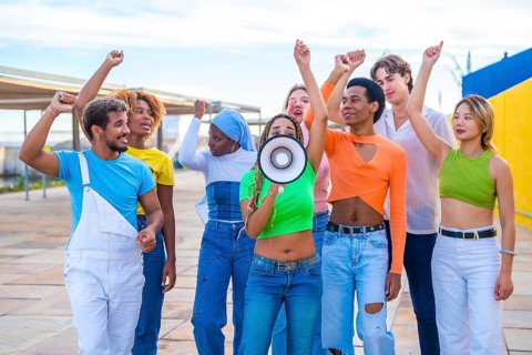 Multicultural and gender diverse young people yelling using a loudspeaker in a protest on an urban