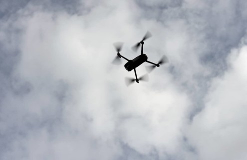 Silhouette of a drone in flight backlit against the sky, Switzerland