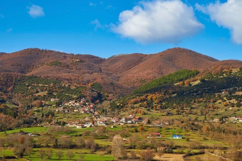View of a village surrounded by autumnal hills and meadows, Erymanthos Mountains, northwest of the
