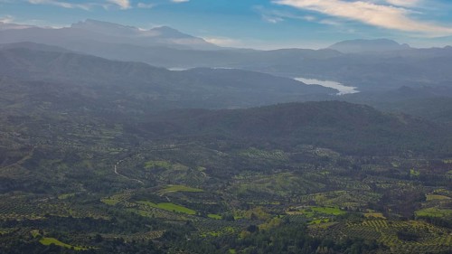 Sky exchanged, Sweeping view of a hilly, green landscape with mountains in the background under a