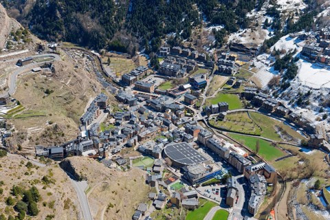 Blick auf eine kleine Stadt im Gebirgstal von Andorra mit verschneiten und grünen Flächen. Klar