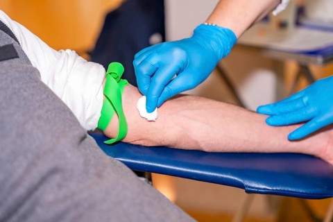Nurse cleaning the area she is going to prick on the arm of a blood donor using a cotton swab