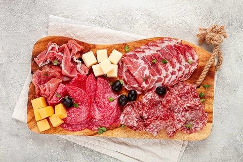 Assorted, sliced meat appetizer, prosciutto, salami and ham, with cheese and olives, on a wooden