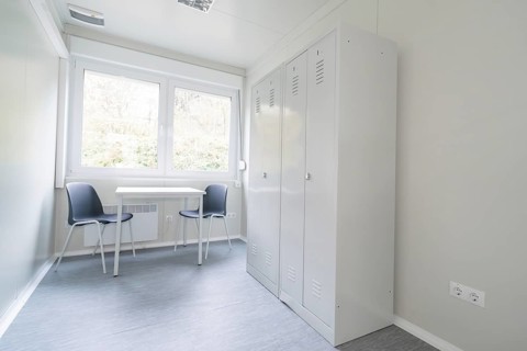 Simple office with desk, two chairs, a cupboard and large window, refugee accommodation Beermiß,