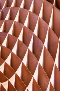 Close-up of an abstract, rhythmic arrangement of alternating rusty and white metal fins forming a