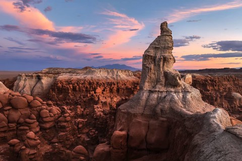Majestic sandstone formations in Goblin Valley State Park, Utah, glow under a vibrant sunset sky,
