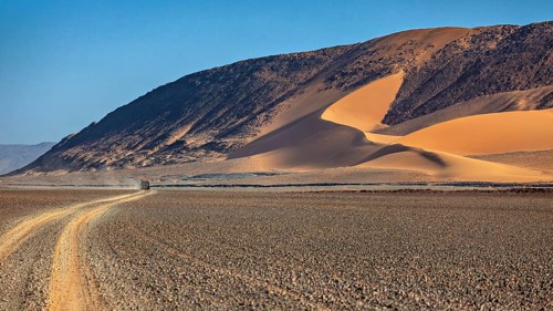 Majestic, curved sand dunes on the edge of a desert road, The landscape of the Sahara in Algeria