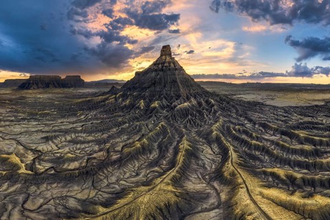 Dramatic sunset casts vibrant colors over the unique, eroded landscape of Factory Butte, Utah,