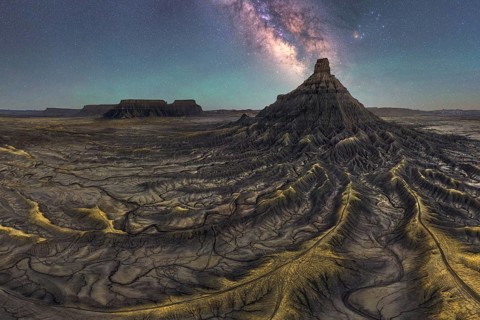 A breathtaking view of the Milky Way galaxy illuminating a majestic sandstone desert landscape in