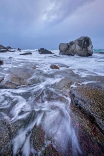 Rocks on beach of fjord of Norwegian sea in winter on sunset. Utakliev beach, Lofoten islands,