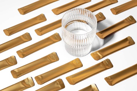 From above a golden jelly collagen sachets arranged on a white background alongside a transparent