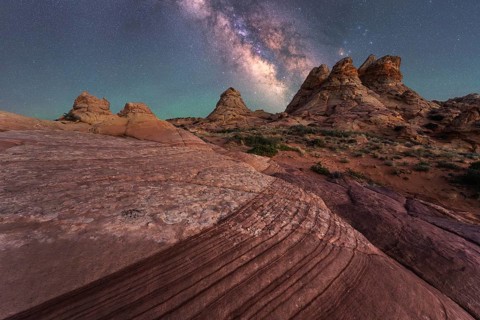 Stunning view of the Milky Way illuminating a rocky desert with unique formations, capturing the