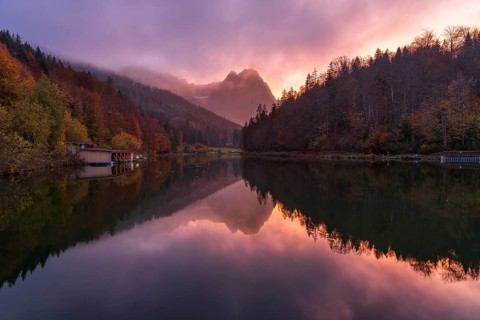 A stunning sunset at Riessersee in the Bavarian Alps casts vivid colors over calm waters,