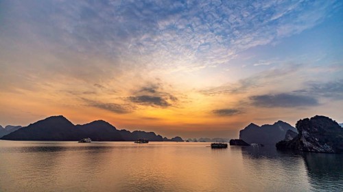 Wide sky at sunset over still water and distant rocks, sunset in Halong Bay, Vietnam