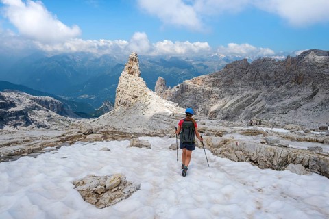 Female hiker on hiking trail 305 crossing a snowfield, Brenta Mountains, Parco Naturale