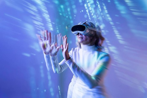 An elderly Asian woman engages with the metaverse using a virtual reality headset. She extends her