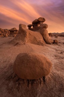 Dramatic sandstone formations under a vibrant sunset sky in Goblin Valley State Park, Utah, USA.