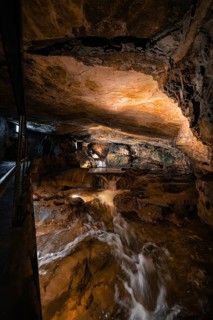 Rushing watercourse in a hilly cave environment, illuminated, adventurous, Beatus Caves,