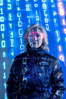 An elderly Asian woman wearing futuristic eyewear is immersed in the metaverse. Blue digital code