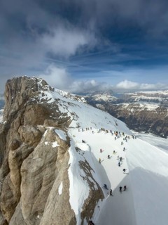 View of the snow-covered Marmolta (3343 m) with skiers in the foreground and clouds in the