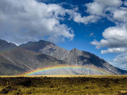 A stunning autumn scene at Mount Cook, New Zealand, showcasing a vibrant rainbow arching over lush