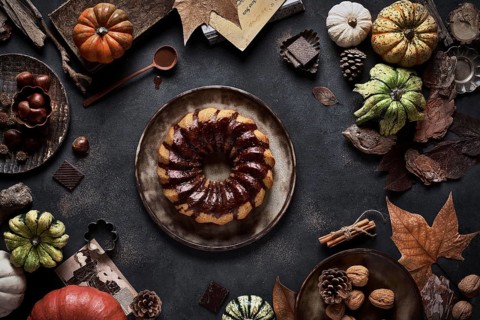 From above tasty appetizing pumpkin cake with chocolate cream on table decorated with autumn