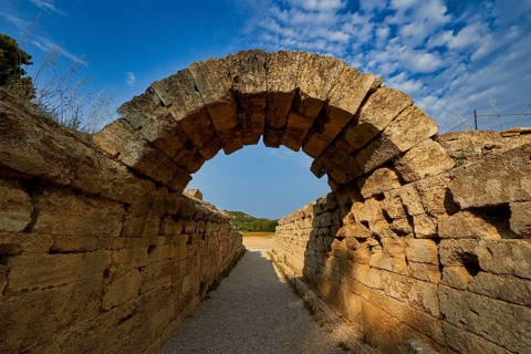 Crypt, vaulted walkway to the stadium, old stone arch leading through massive walls under a blue