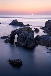 Coastal landscape at Land's End. The Enys Dodnan Arch with rock gate. In the evening at sunset.