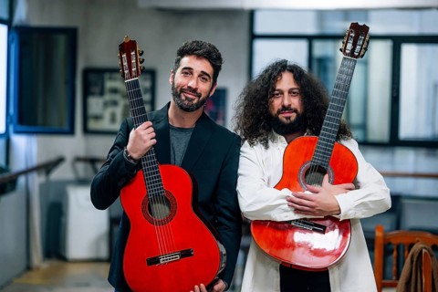 Portrait of confident male artists carrying red bass guitars in music studio