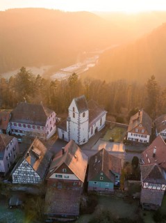 Half-timbered houses and a church in warm sunset light look idyllic and peaceful, Zavelstein, Calw