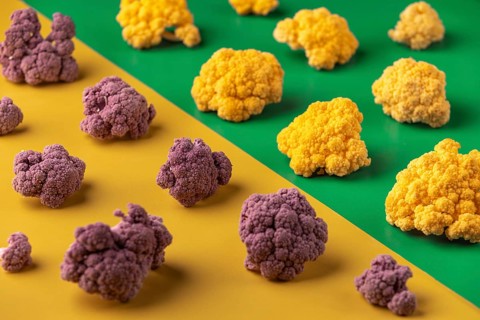 Purple and yellow cauliflower arranged on a yellow and green background