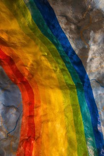 A colorful rainbow mural painted on a textured wall in Stockholm. The vivid hues contrast with the