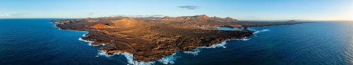 Coast with lava fields, volcanic landscape near Los Hervideros with red volcano Montaña Bermeja, in