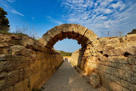 Crypt, vaulted entrance to the stadium, ancient stone arch on a narrow hiking trail under a clear