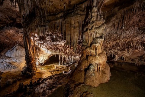 Stalactites and stalagmites, rock formations in a stalactite cave with water basin, Grotta del