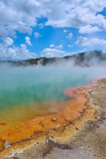 A hot spring with colourful rim and rising steam, Champagne Pool thermal lake, Wai-O-Tapu Thermal