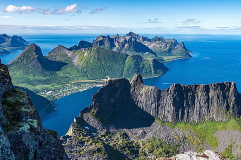 Aerial view from top of Mt. Grytetippen towards village Fjordgard, Mt. Segla and Mt. Hesten, Senja