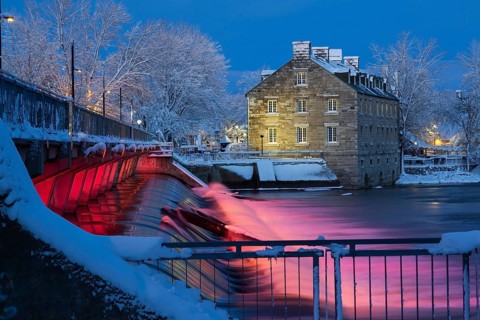 Illuminated Moulin Neuf water flow control dam and walkway over Des Mille-Iles river plus New Mill
