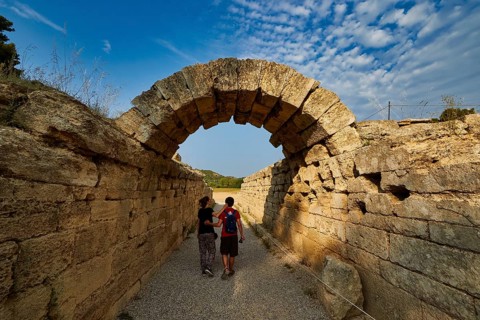 Crypt, vaulted passage to the stadium, two people walking through an ancient stone arch pass under