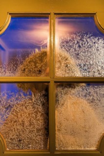 Frost-covered window with a blurred figure seen through the glass, capturing the essence of a cold