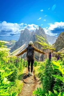 Hiker walking along a path with open arms, enjoying the view of the odle mountains in the italian