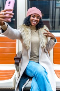 Cheerful young woman takes a selfie on public transport, making peace sign with fingers while