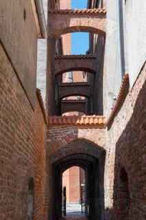 A narrow, arched passageway made of bricks with historical flair, 13th century church path, Elblag,